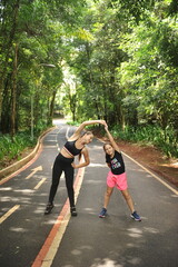 mãe e filha fazendo exercicios de alongamento ao ar livre em parque, treino livre - obrazy, fototapety, plakaty