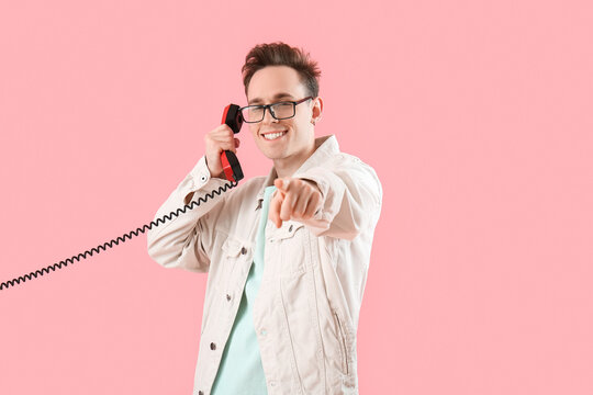 Cool young man talking by phone on pink background