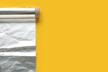 Roll of aluminium foil on yellow background