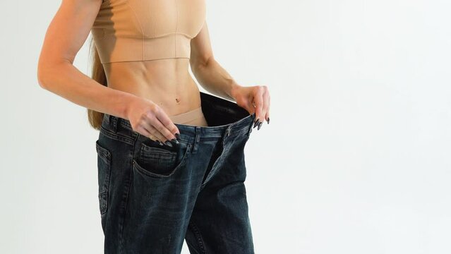Woman in oversize jeans after weight loss, diet concept