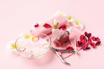 Composition with bottles of cuticle oil, manicure instruments and flowers on color background
