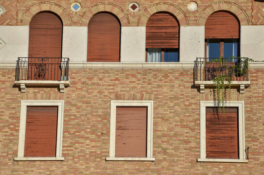 Windows on a building made of bricks. Building in Padua, Italy. Windows with lowered blinds.