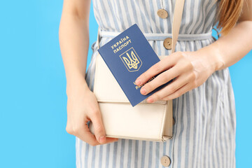 Fototapeta na wymiar Woman with Ukrainian passport and bag on blue background, closeup