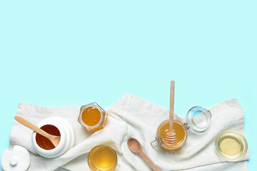 Jars and bowls with sweet honey on blue background