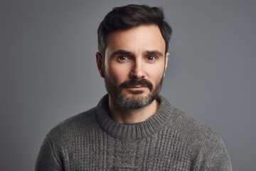 Portrait of a bearded man in a gray sweater on a gray background