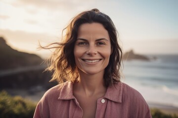Portrait of smiling woman looking at camera on the beach at sunset