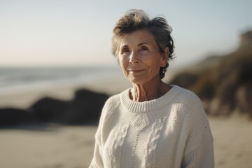 Portrait of smiling senior woman standing on beach at autumn day.