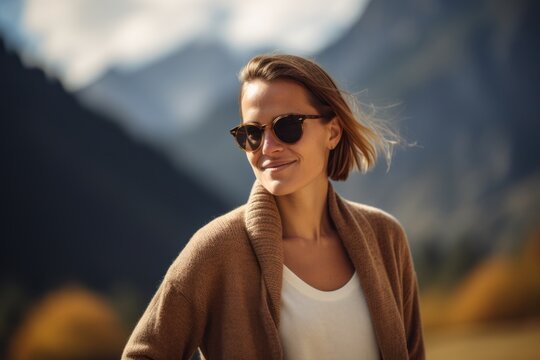 Portrait of a beautiful young woman in sunglasses on the background of mountains