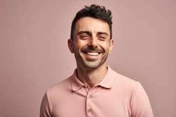 Obraz premium Portrait of a happy young man smiling on a pink background.