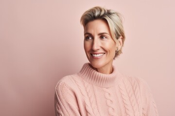 Portrait of smiling mature woman in sweater looking away isolated on pink background