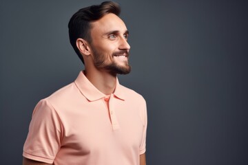 Obraz premium Portrait of a smiling young man in polo shirt looking away over gray background