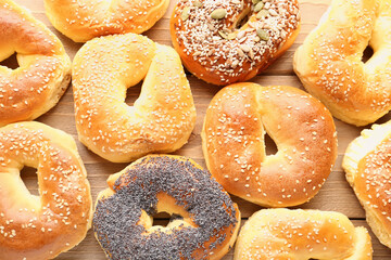 Tasty bagels with sesame and poppy seeds on wooden background, closeup