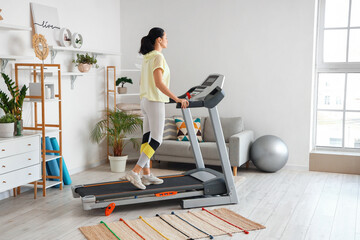 Fototapeta premium Beautiful woman training on treadmill at home