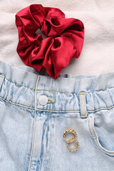 Silk scrunchy with jeans and rings on white fabric background, closeup