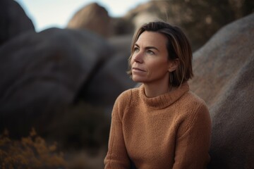 Beautiful young woman in a brown sweater on a background of rocks