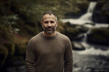 Portrait of a handsome middle-aged man on a background of a waterfall