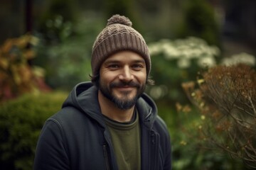 Portrait of a handsome young man with beard and hat in the garden