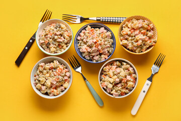 Bowls of tasty Olivier salad on yellow background