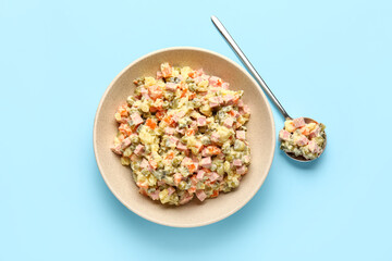 Bowl of tasty Olivier salad on blue background