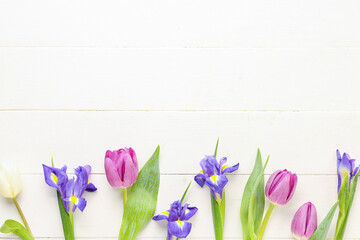 Tulips with iris flowers on white wooden background