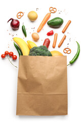 Fototapeta na wymiar Paper bag with vegetables, sausage and fruits on white background