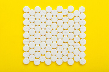 White pills on yellow background