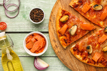 Plate of tasty seafood pizza and ingredients on light wooden background, closeup