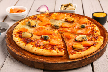 Plate of tasty seafood pizza on light wooden background