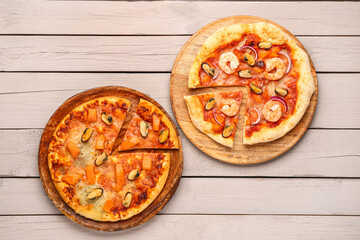 Plates of tasty seafood pizza on light wooden background