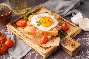 Delicious sandwich with fried egg, tomatoes and bacon on grunge grey background
