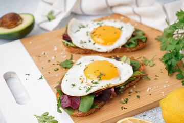 Delicious sandwiches with fried eggs on light background
