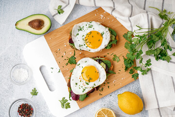 Delicious sandwiches with fried eggs on light background