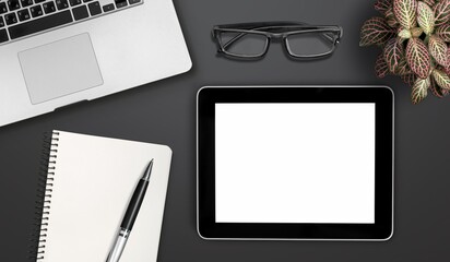 Tablet computer with blank screen, cup and supplies on desk.