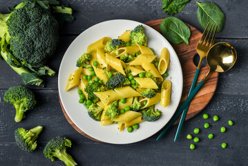 Plate with tasty penne pasta and broccoli on dark wooden background