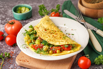 Tasty omelet with vegetables on grey grunge background