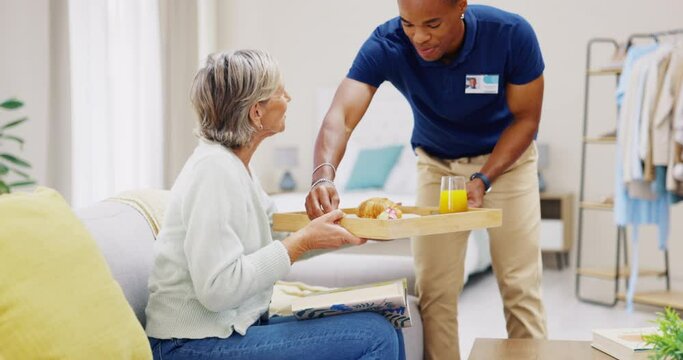 Breakfast, assisted living and retirement with a old woman on a sofa in the living room of her home. Morning, food and a nurse black man serving a meal to an elderly patient in a care facility