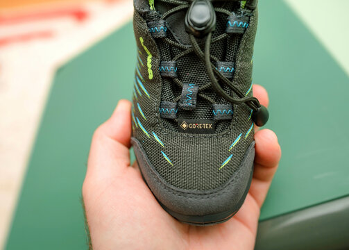 POV male hand holding new Gore-Tex baby shoes high-quality German lowa shoes for unique outdoor experiences