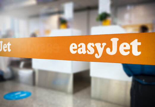London, UK Jan 2023: Orange retractable belt barrier with the Easyjet logo inside an airport. Easyjet is a British multinational low-cost airline. Travel and airport security. Illustrative editorial
