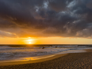 Fototapeta na wymiar Dramatic sunset over Atlantic ocean in Portugal with dark, moody clouds in the sky