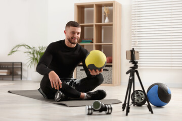 Trainer with ball streaming online fitness lesson on phone at home