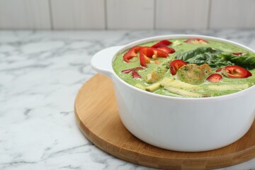 Saucepan with delicious green curry chicken soup on white marble table. Space for text