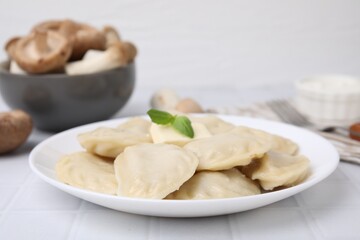 Delicious dumplings (varenyky) with tasty filling and butter on white tiled table, closeup