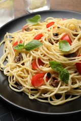 Delicious pasta with anchovies, tomatoes and basil on plate