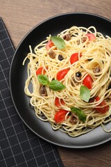 Delicious pasta with anchovies, tomatoes and basil on wooden table, top view