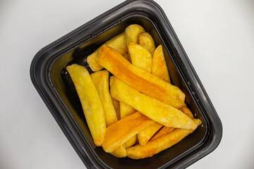 A plate of french fries in a plastic box, on red background