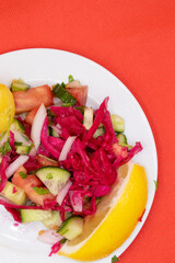 Colorful, healthy salad on a plate on a red background.