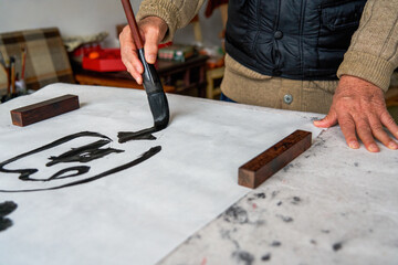 An old Chinese calligrapher is creating and writing calligraphy works.
Translation: carry on the...