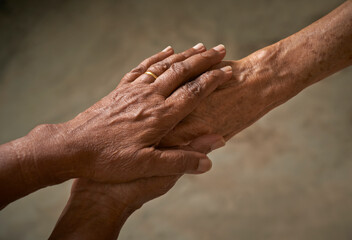 Caregiver, carer hand holding elderly hand. People helping and comforting each other concept.