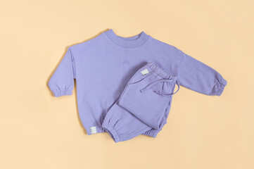Stylish lilac children's spring, autumn sport costume. Soft touch, warm joggers and sweatshirt. Fashion kids outfit for spring, autumn and winter. Flat lay, top view.
