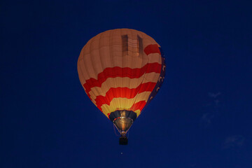 Naklejka premium A beautiful hot air balloon lights up the night sky as the propane flame bursts into the balloon at the annual Albuquerque International Balloon Fietsa.
